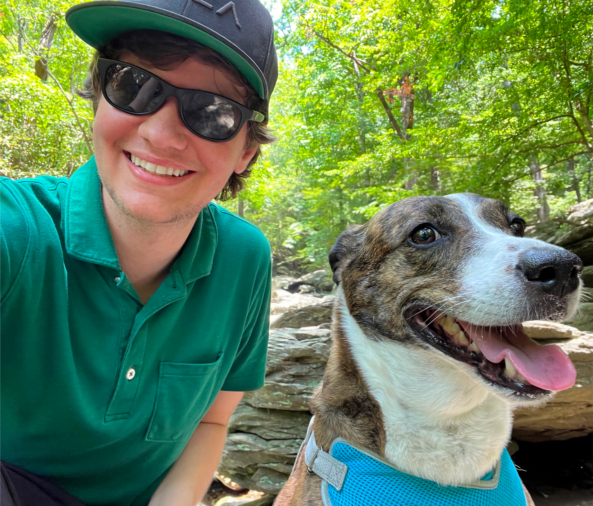 Jared and Brindle Jared with his dog Brindle in an outdoor wooded setting with boulders